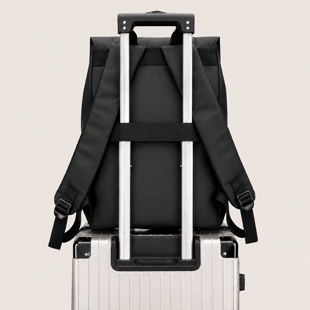 The black DRAEN backpack on a suitcase, its rear trolley sleeve over the handle
